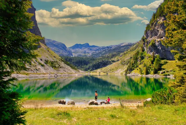 Un paesaggio panoramico della Slovenia, con dolci colline verdi, laghi cristallini e maestose montagne sullo sfondo.