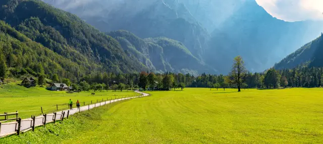 Un paesaggio sereno con dolci colline, verde lussureggiante e un cielo azzurro, che mostra la bellezza naturale della Slovenia.